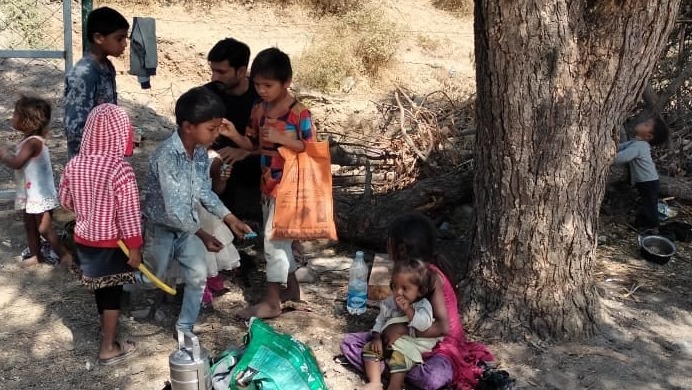 A field facilitator standing with a group of children and adults during a visit to labour families in Chital